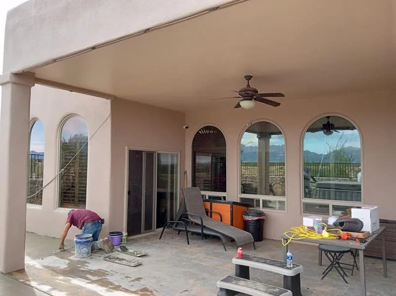 Repair work on the floor of a covered stucco patio with arched windows