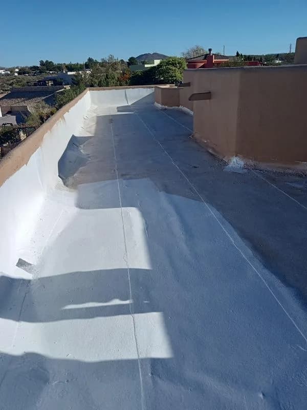 Flat roof part-way through recoating, white coating over grey along a parapet