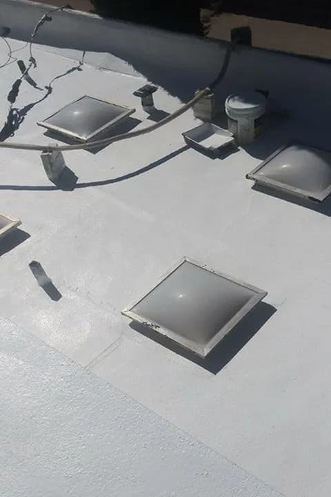Coated flat roof with several domed skylights, their curbs sealed