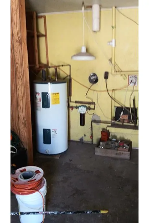 Tank water heater standing in a garage utility corner